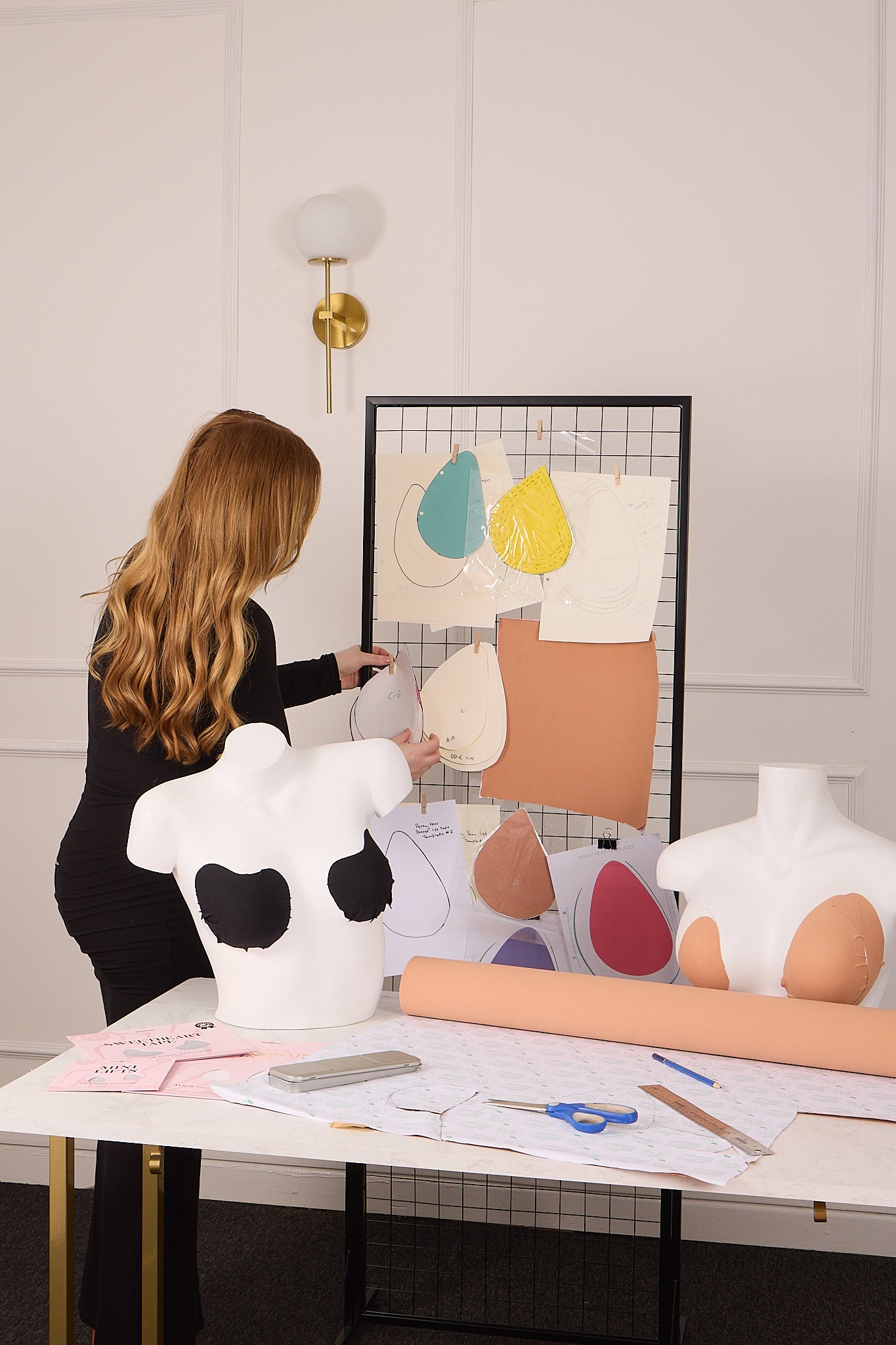 Person working with fabric samples and a mannequin in a design studio.