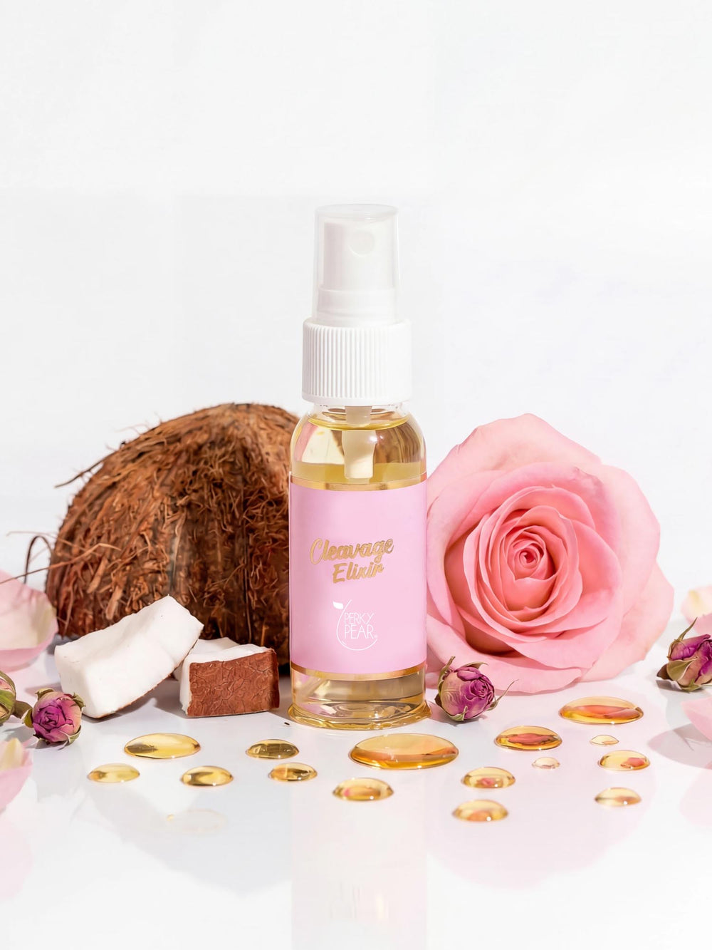 Bottle of 'Cleavage Elixir' with a pink label, coconut, and pink rose on a white background